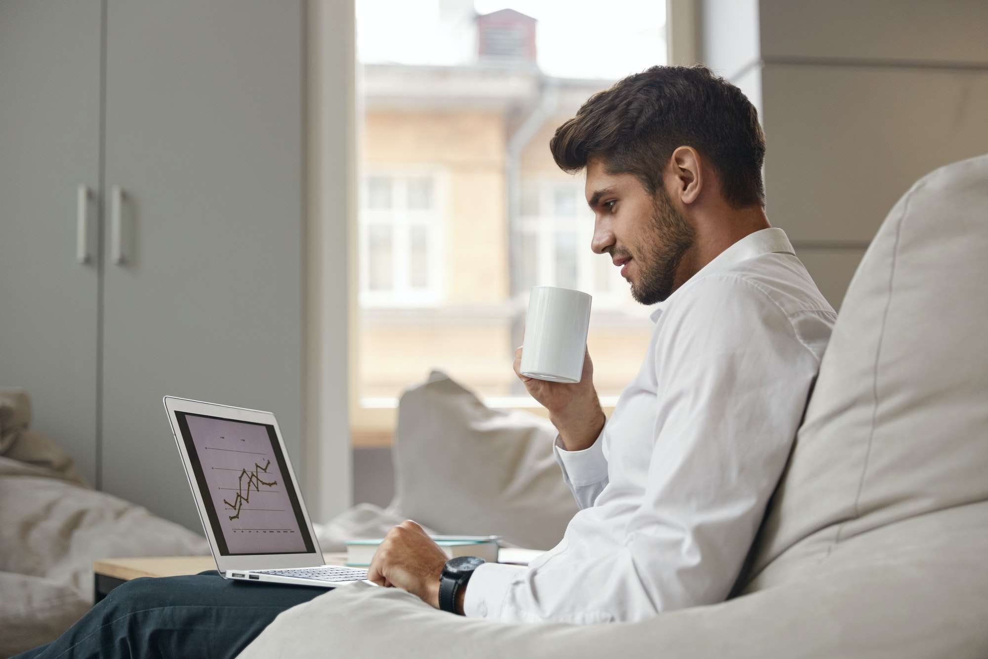 Businessman drink coffee and watch graph on laptop